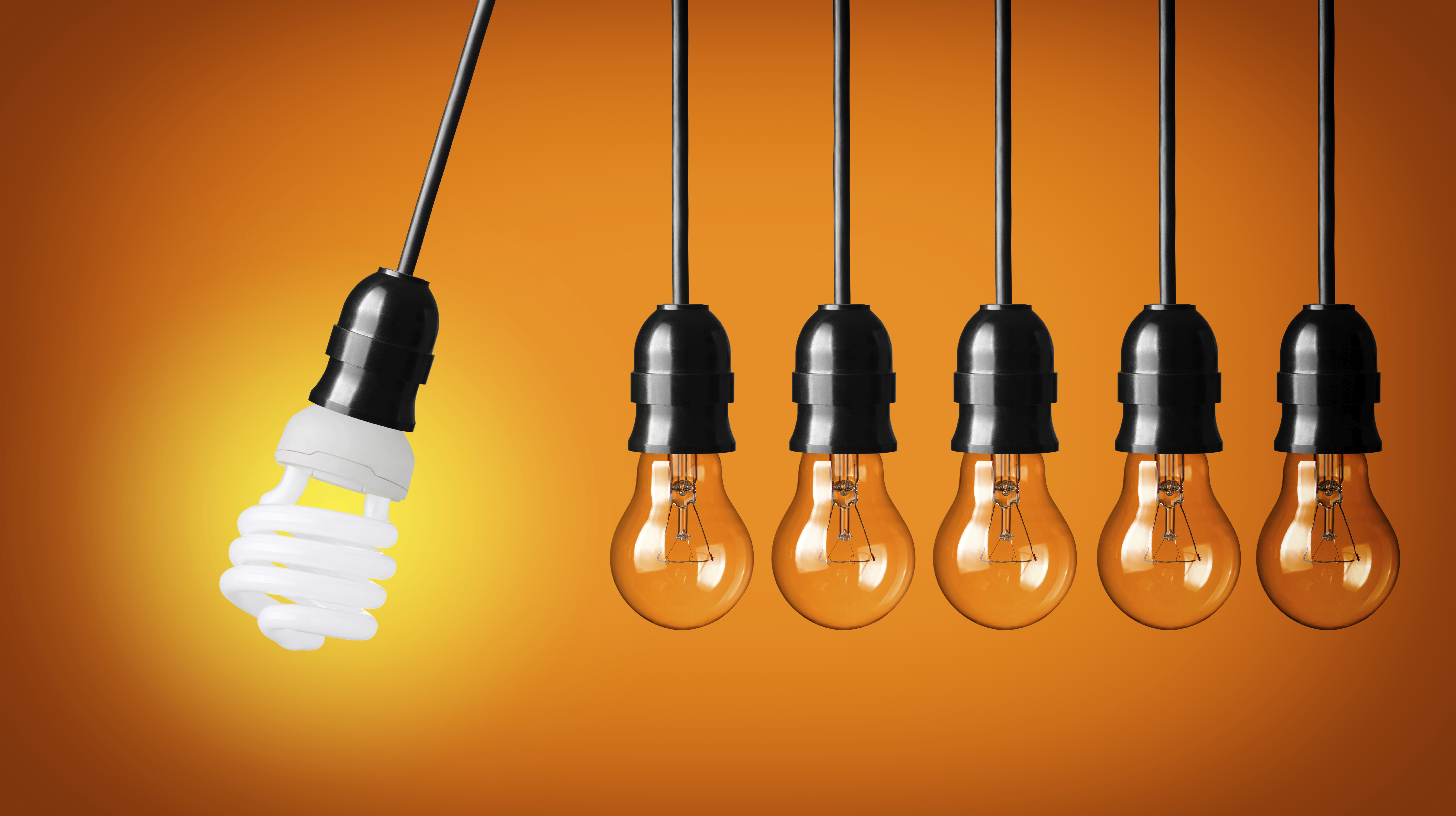 Perpetual motion with light bulbs and energy saver bulb. Idea concept on orange background.